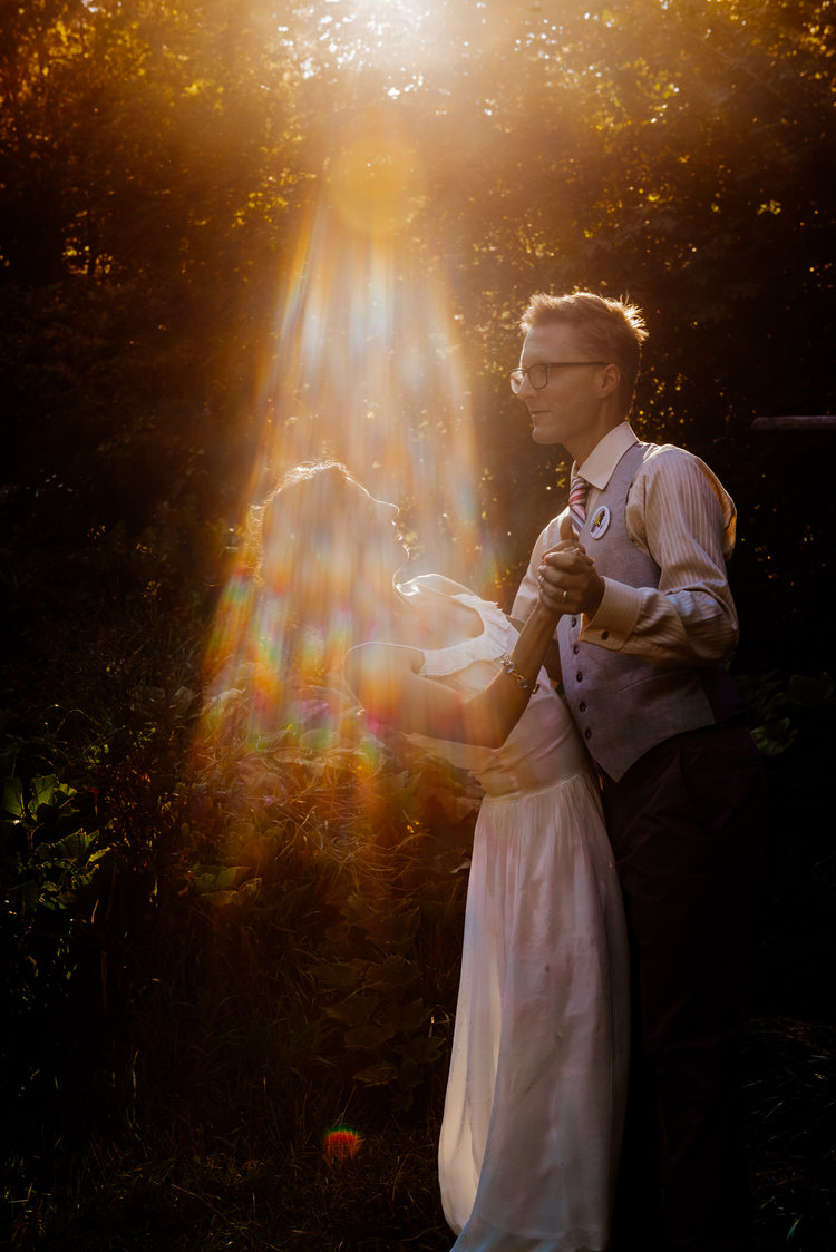 Couple dances in a sunbeam at colorful rustic outdoor wedding