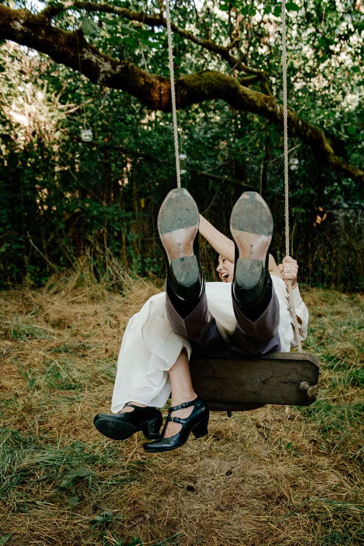 Newlyweds on a rope swing at a colorful outdoor wedding
