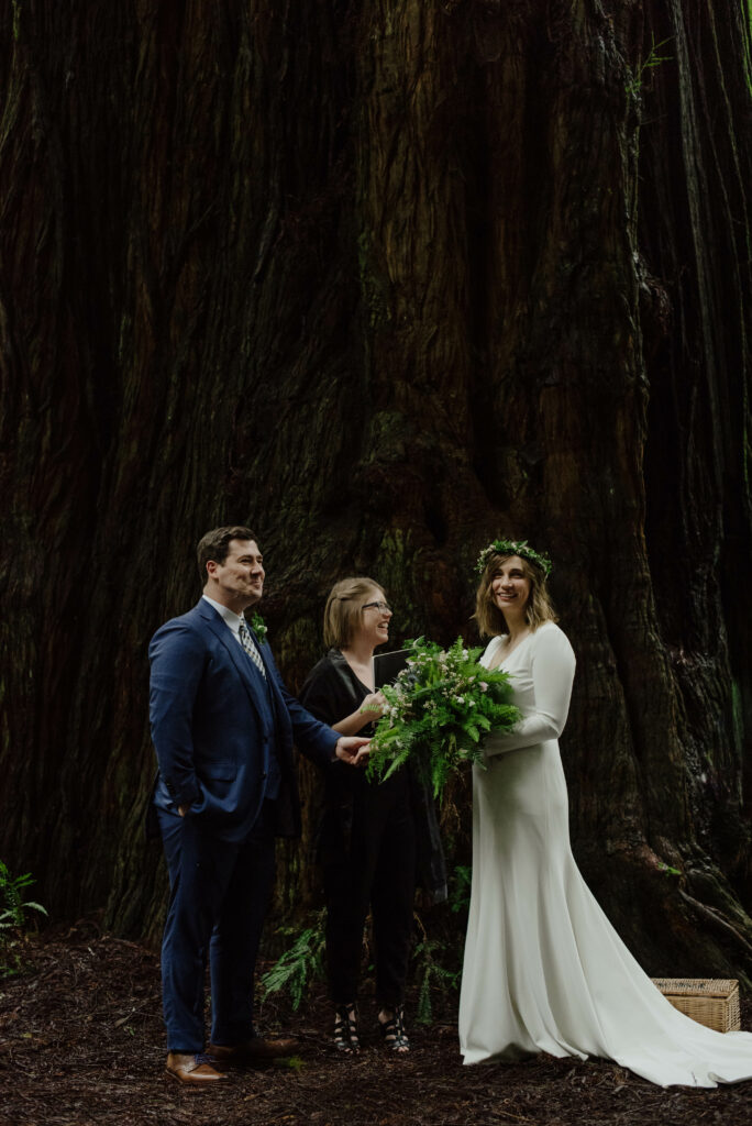 Couple with officiant next to a giant redwood tree in Prairie Creek Redwoods