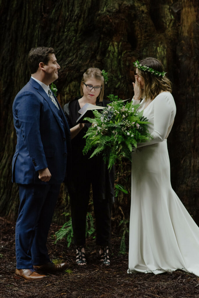 Bride wipes away tear during wedding ceremony in Northern California redwoods