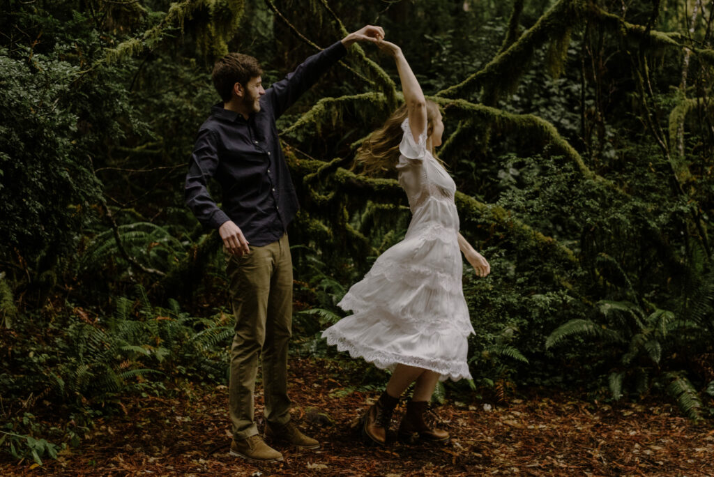 Engaged couple twirls in the redwood forest at Prairie Creek Redwoods during their engagement session.
