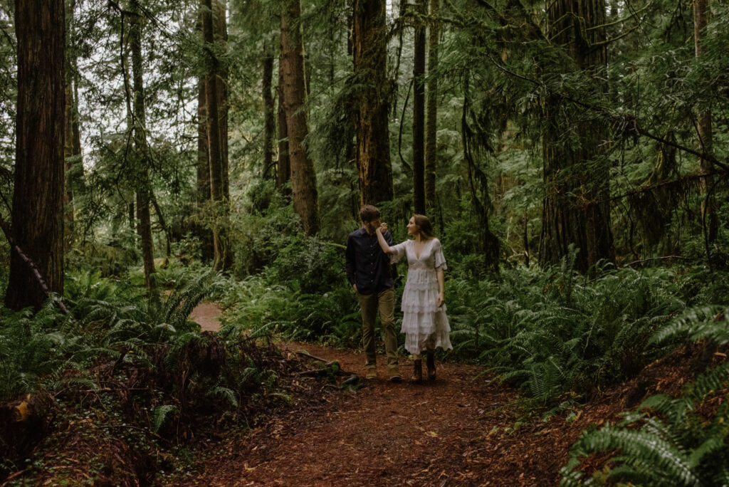 Portrait of engaged couple in redwood forest with a lace dress and doc martens
