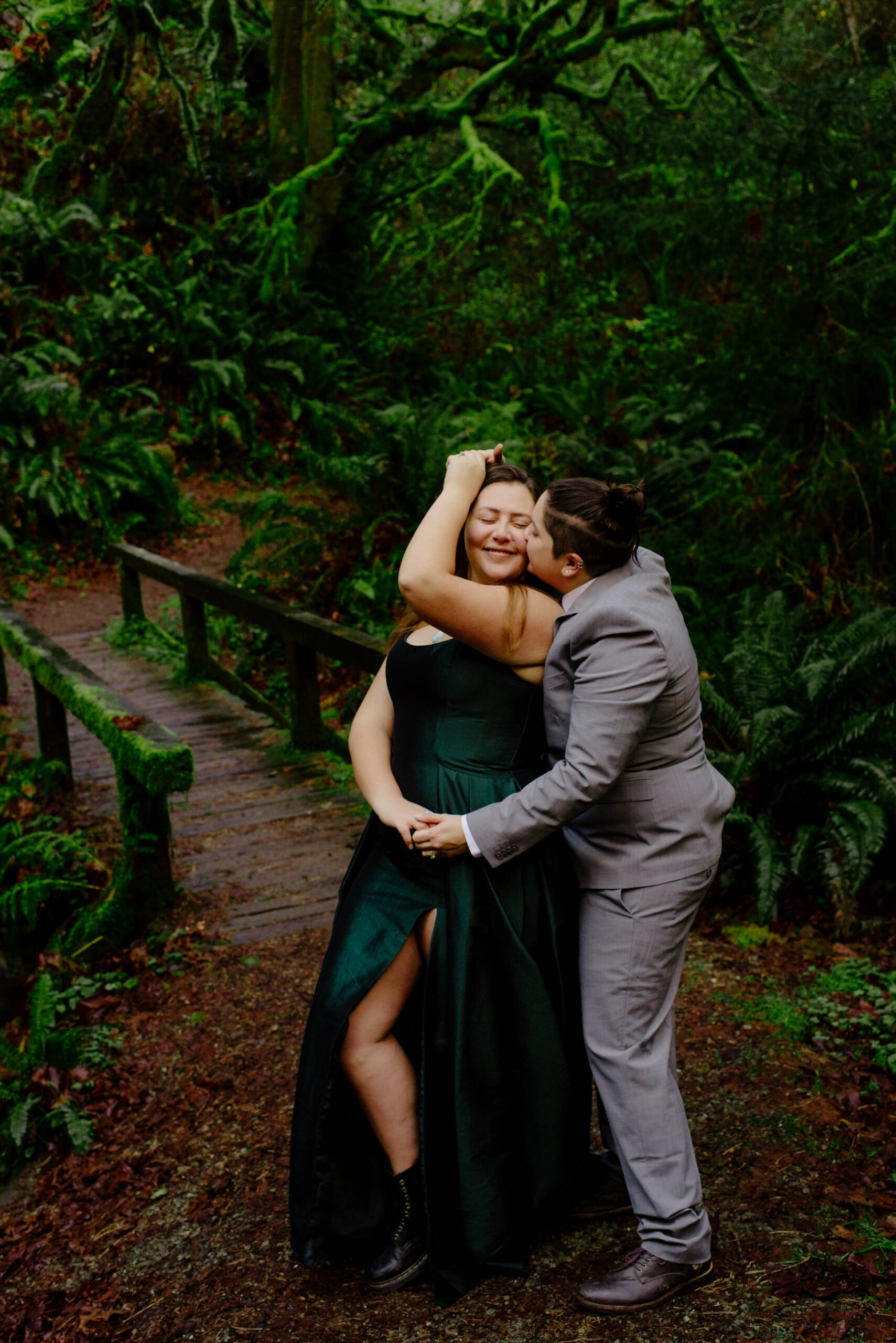 Two brides laugh during forest engagement session in Northern California