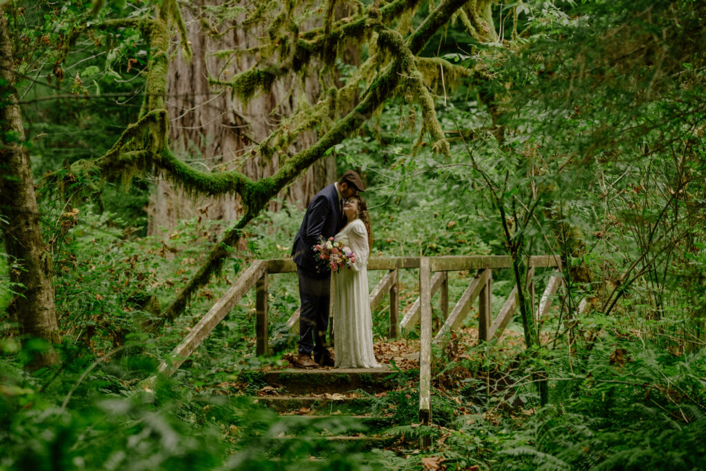 Bride and groom on bridge in redwood forest