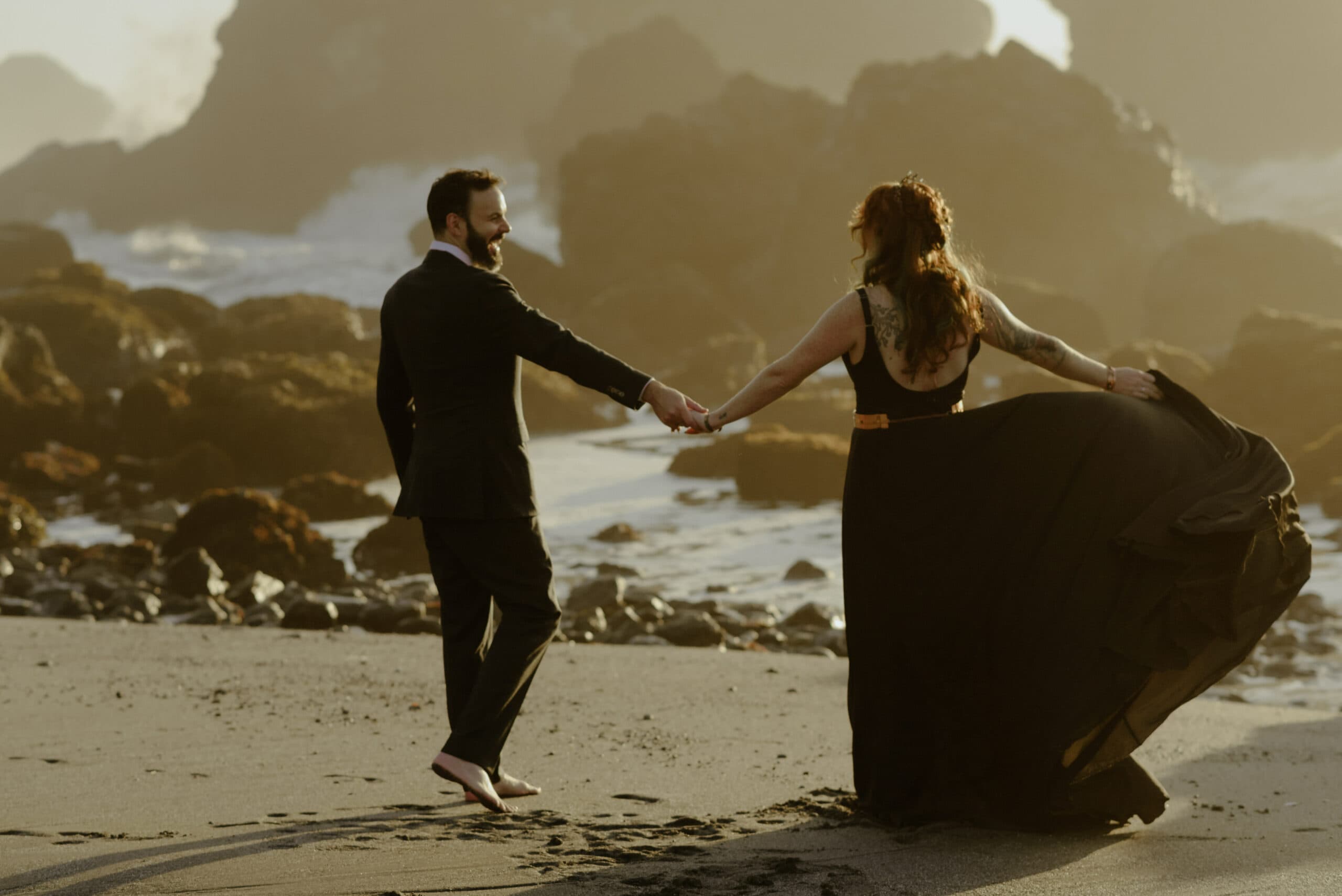 Amanda and Will twirl on Luffenholtz Beach at golden hour following their redwood coast elopement on the Avenue of the Giants.
