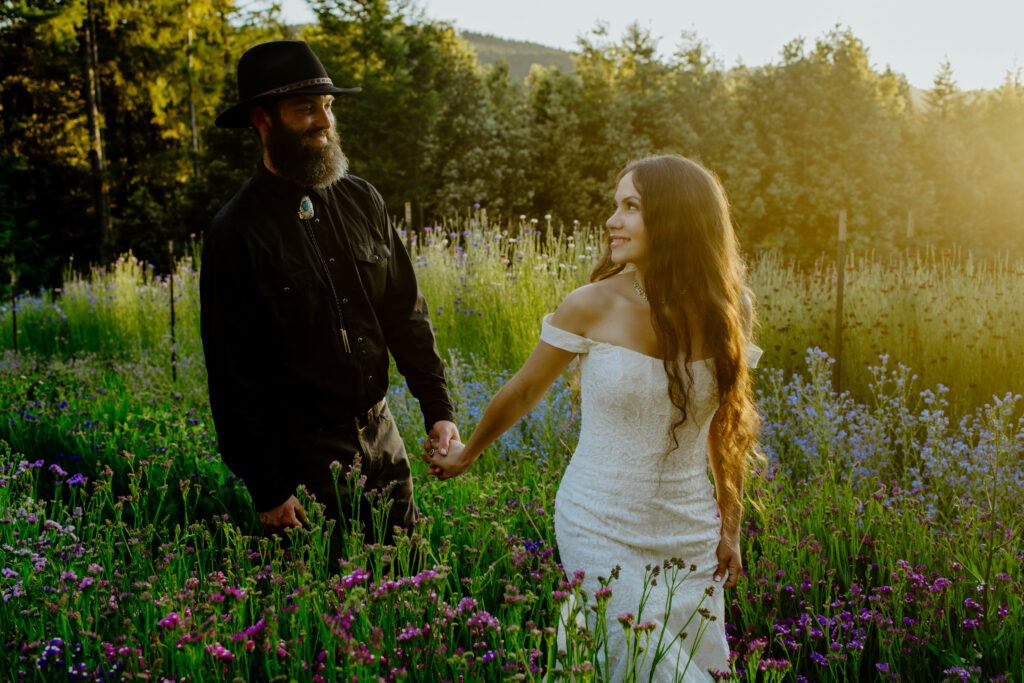 Bride leads groom through their flower fields at golden hour near the Trinity mountains in Humboldt County
