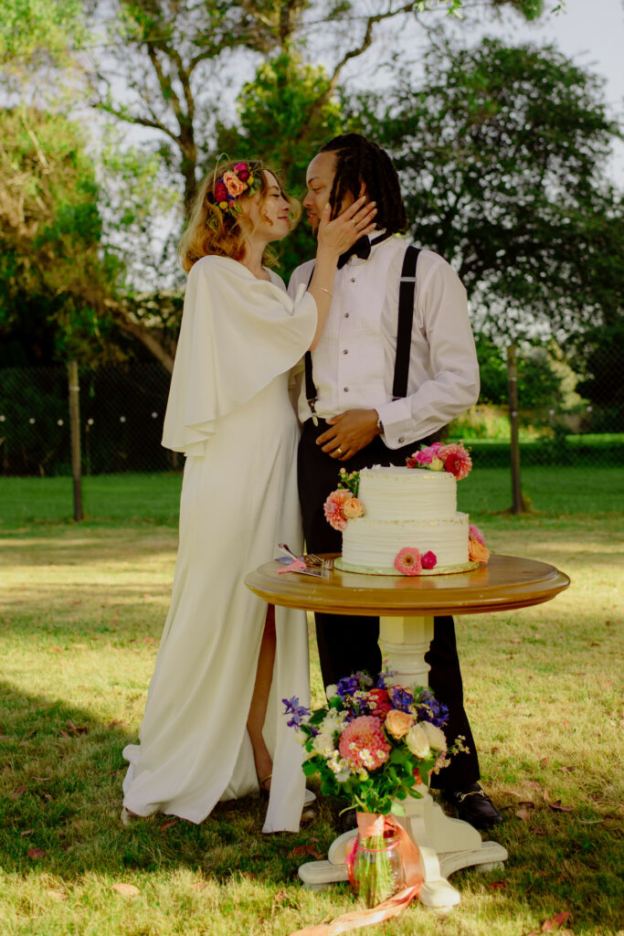 Newlyweds cutting cake at back yard wedding in California.