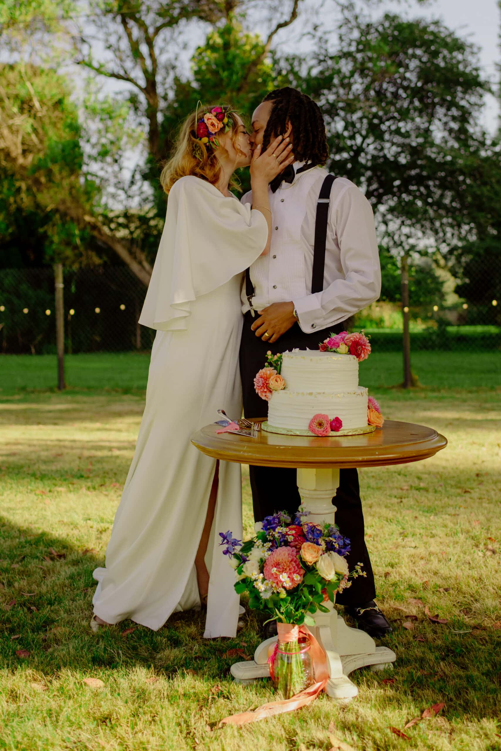 Bride and groom kiss during cake cutting in Northern California garden