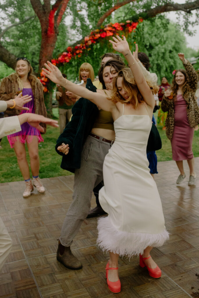 Bride dances in orange platform heels at Northern California garden wedding reception