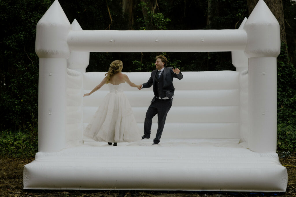 Bride and groom hold hands in bouncy castle at Humboldt County wedding