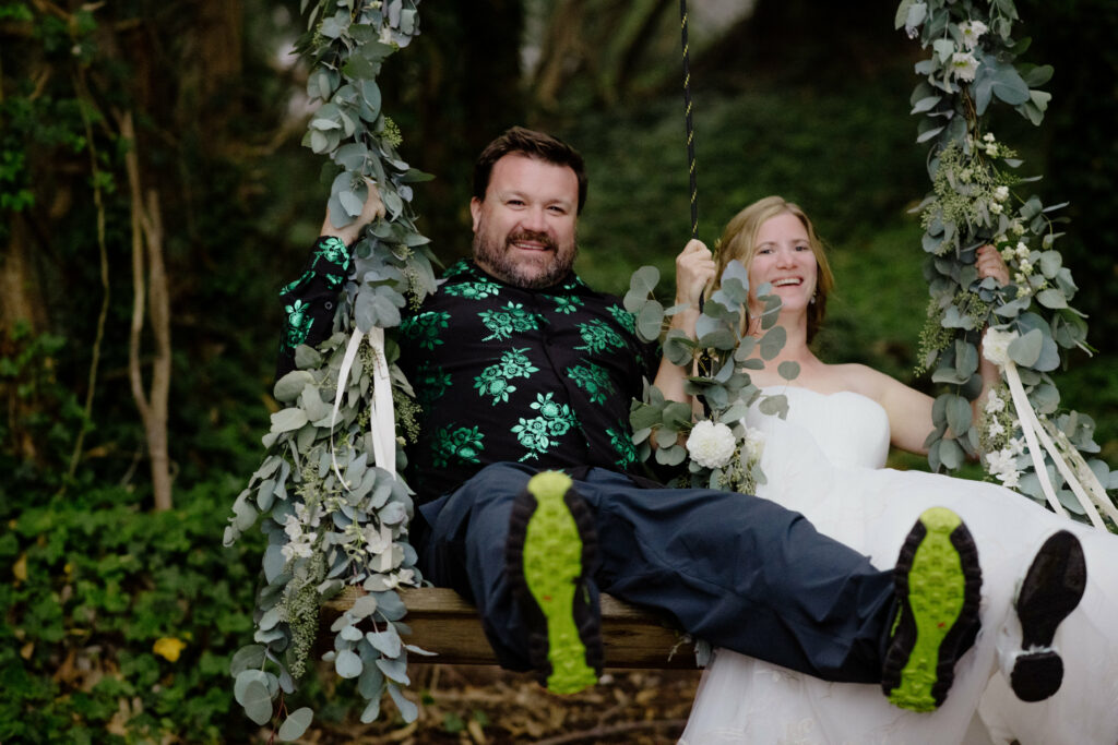 Bride and brother in dinosaur print button down on floral swing in the Oyster Beach eucalyptus trees at Humboldt Bay Social Club