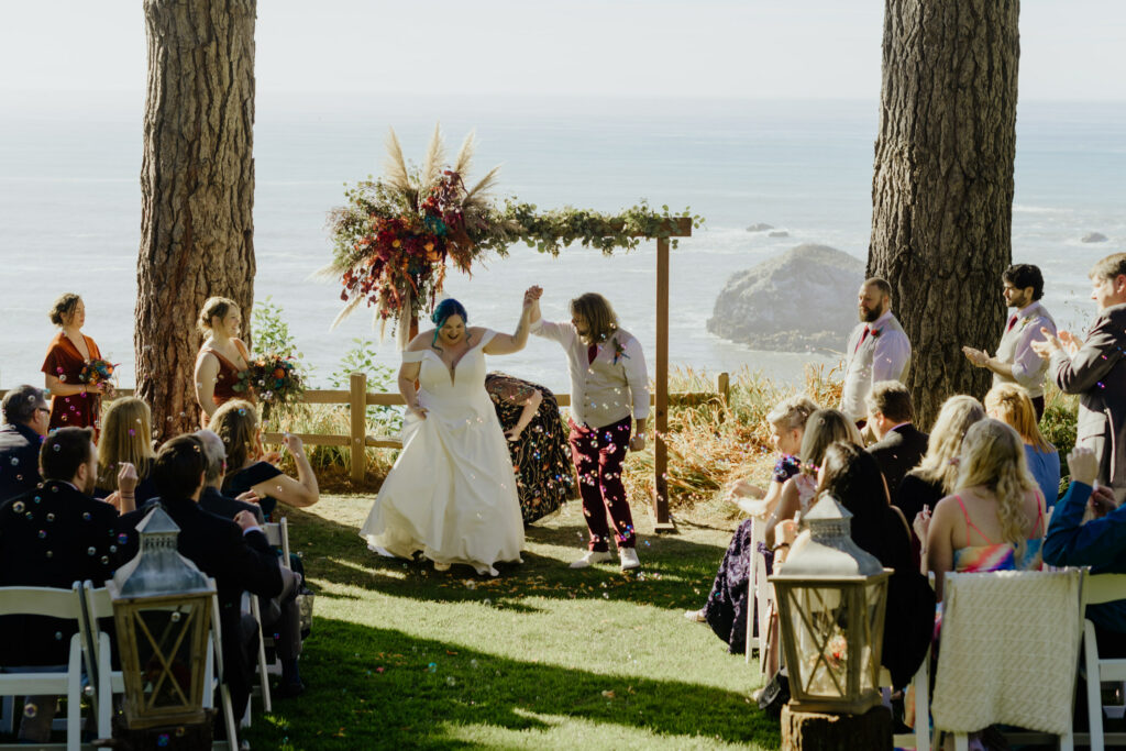 Guest blow bubbles as newly married couple proceeds down aisle after redwood coast ceremony at the Lost Whale Inn in Trinidad, California.
