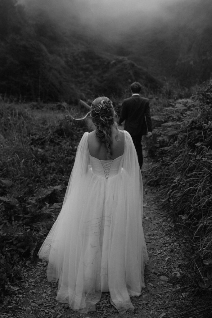 Bride's hair catches the wind as the couple proceeds back down the trail at Wedding Rock