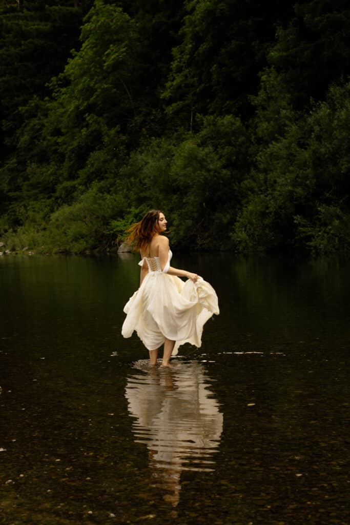 Bride wades in the Eel river in Williams Grove following intimate wedding in the redwoods.
