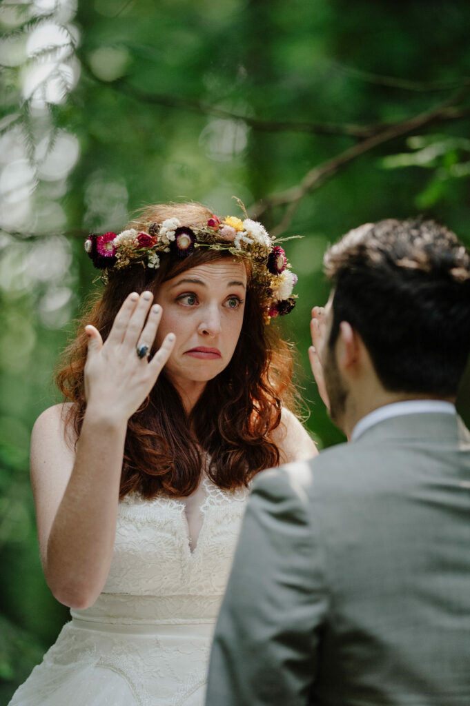 Bride in straw flower crown fans tears during a redwood wedding first look at Pamplin Grove in Humboldt Redwoods.