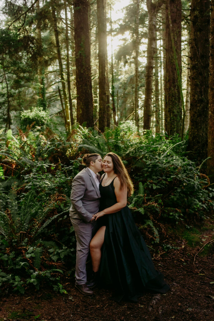 LGBTQ+ bride in green ball gown laughs with partner in grey suit.
