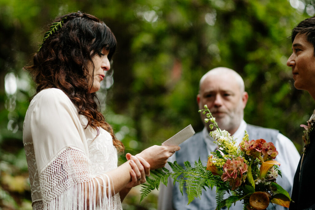 Bride steadies hand as she reads vows in Redwood Park in Arcata, California during elopement