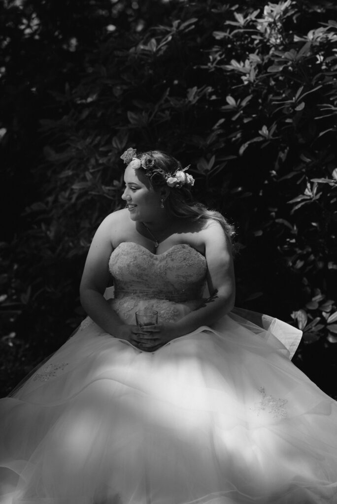 Bride in Monique Lhuillier gown sits in the shade of a garden at the Lost Whale Inn in Northern California.