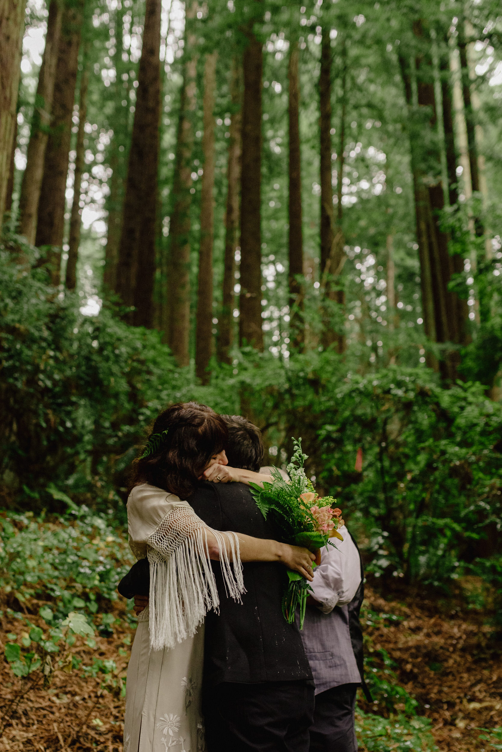 Two brides hug following Humboldt wedding ceremony in Northern California redwood forest