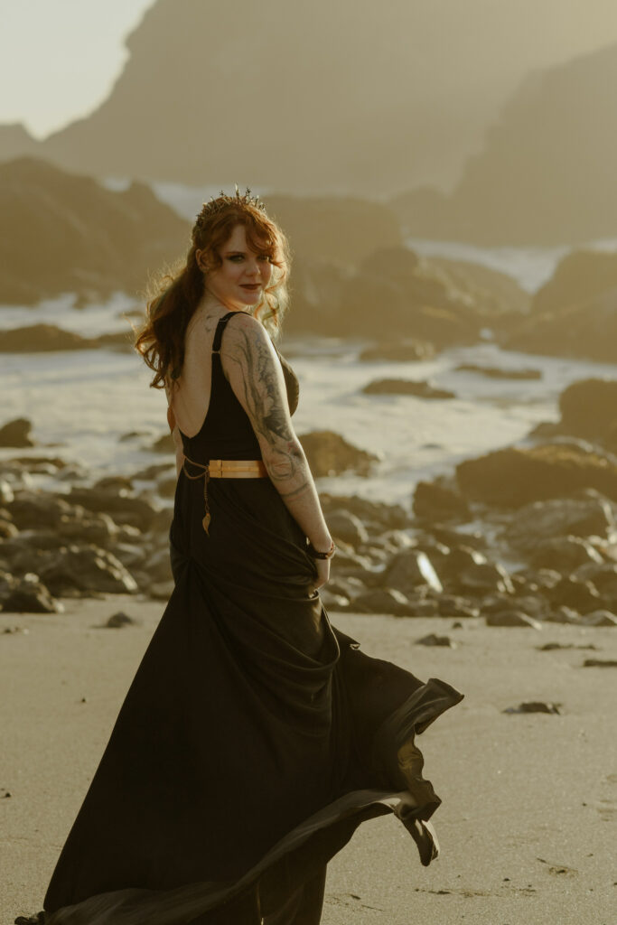 Nontraditional bride in a black gown twirls on the breeze on a Northern California beach