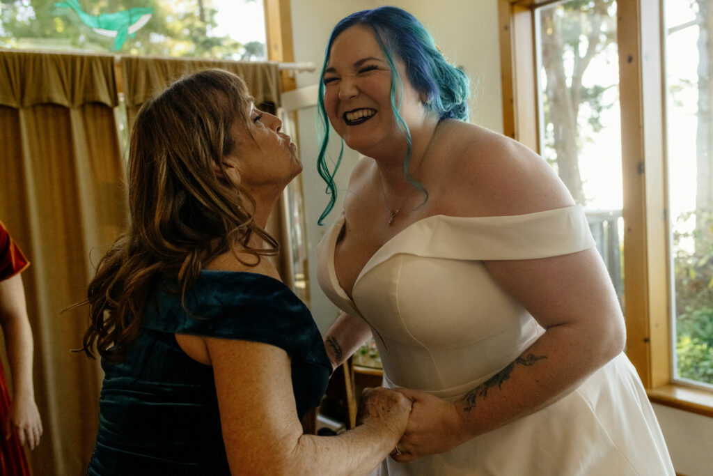 Mom stretches to kiss her daughter before they walk down the aisle together at the Lost Whale Inn in Northern California