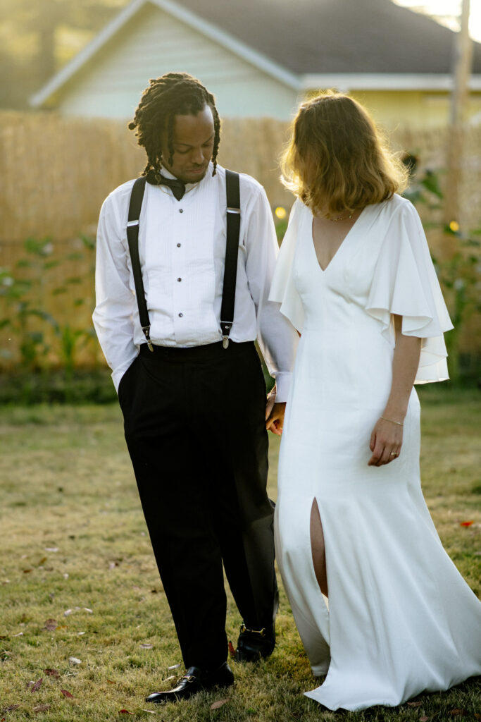 Newly married couple in black tie attire walks through their backyard wedding reception in Northern California