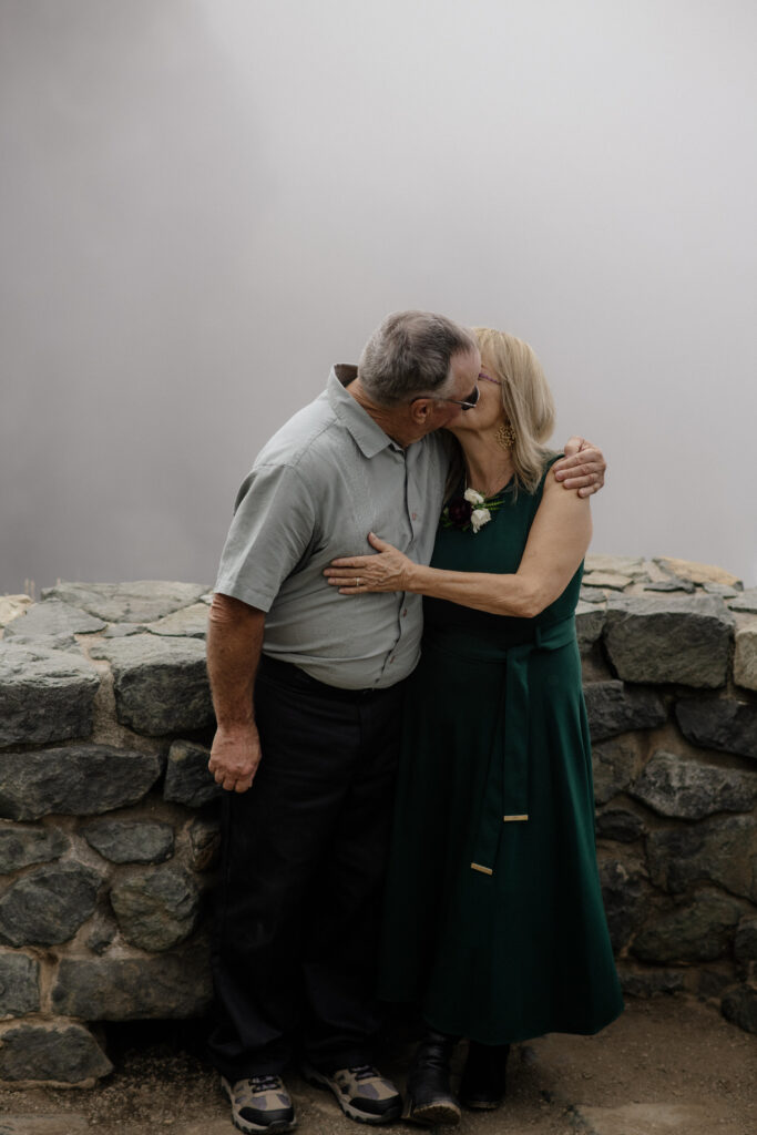 Parents kiss during a wedding portrait session with the Pacific Ocean in the background at Sue-Meg State Park