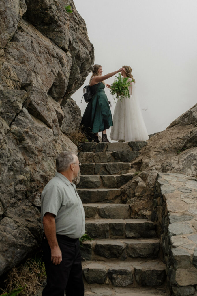 Sister hugs bride before she descends the stone steps to her ceremony at the top of Wedding Rock in Trinidad, California
